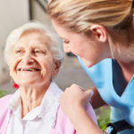 Guardian's hand on senior as they both exchange smiles