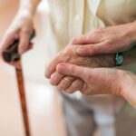 Nurse consoling her elderly patient by holding her hands