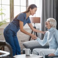 Happy female professional caregiver taking care of elderly woman at home