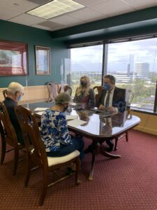 Clients and Attorneys sitting at a desk, separated by plexiglass different angle