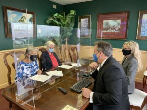 Clients and Attorneys sitting at a desk, separated by plexiglass