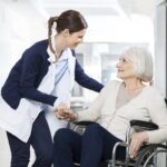 Physiotherapist Consoling Senior Woman Sitting In Wheelchair