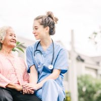 caregiver holding hand of happy elderly woman