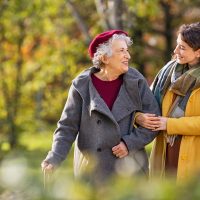 Senior woman walking with granddaughter in park during autumn