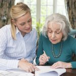 Woman Helping Senior Neighbor With Paperwork