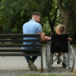 Father with his son in wheelchair at park