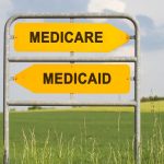 two yellow direction signs with arrows and the words medicare and medicaid, political and social concept for us health care