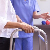 Nurse helping senior woman hand holding walker trying to walk,Care nursing home concept