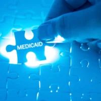 Health Care Concept. Doctor holding a jigsaw puzzle with MEDICAID word.