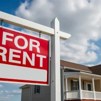 Real estate for rent sign in front of a house